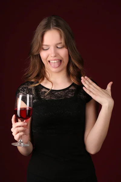Model z winem pokazujący język. Z bliska. Ciemnoczerwone tło — Zdjęcie stockowe