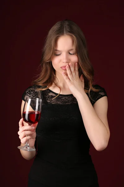 Ragazza con bicchiere da vino che si tocca il viso. Chiudete. sfondo rosso scuro — Foto Stock