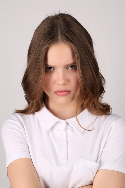 Mädchen mit ernstem Gesicht im T-Shirt. Nahaufnahme. weißer Hintergrund — Stockfoto