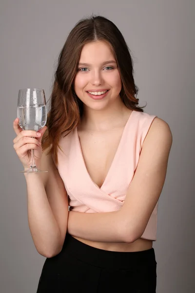 Dame posiert mit Weinglas Wasser. Nahaufnahme. grauer Hintergrund — Stockfoto