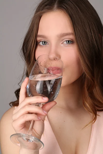 Signora che beve acqua da un boccale. Chiudete. Fondo grigio — Foto Stock