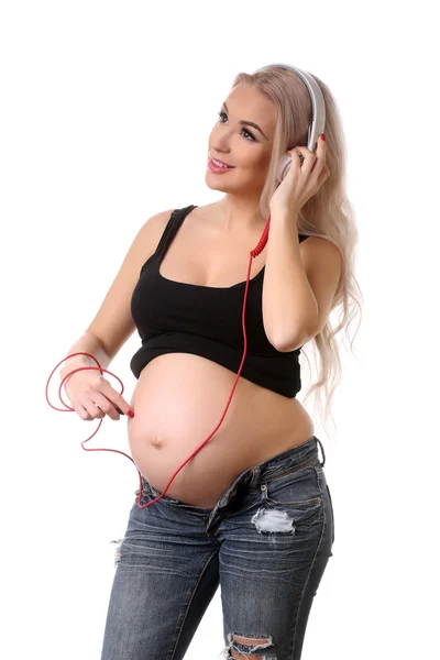 Gravid flicka lyssnar musik via hörlurar. Närbild. Vit bakgrund — Stockfoto