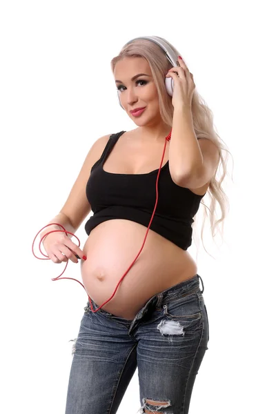 Gravid flicka lyssnar musik med hörlurar. Närbild. Vit bakgrund — Stockfoto