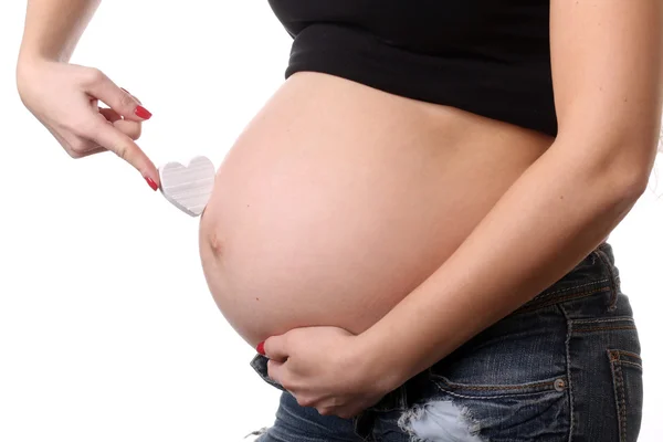 Zwanger meisje met hart symbool. Close-up. Witte achtergrond — Stockfoto