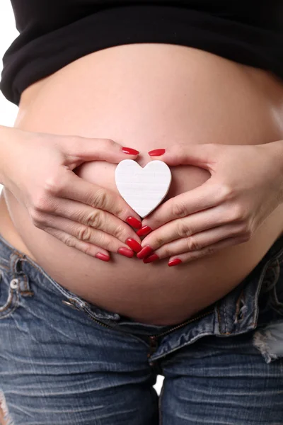 Zwangere vrouw met hart symbool. Close-up. Witte achtergrond — Stockfoto