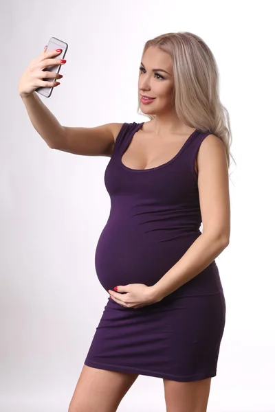 Chica embarazada en un vestido tomando selfie. De cerca. Fondo blanco — Foto de Stock
