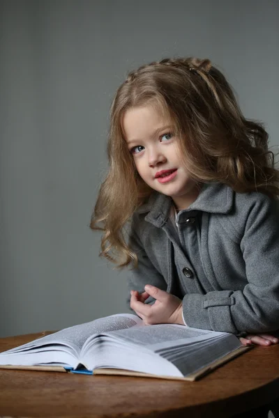 Niña con abrigo y libro. De cerca. Fondo gris —  Fotos de Stock