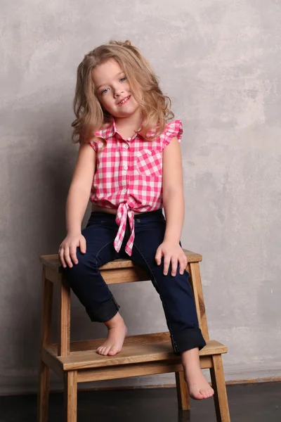 Kleine dame zittend op een stoel. Grijze achtergrond — Stockfoto
