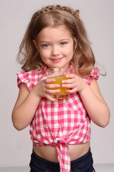 Lite blondin dricker apelsinjuice. Närbild. Grå bakgrund — Stockfoto