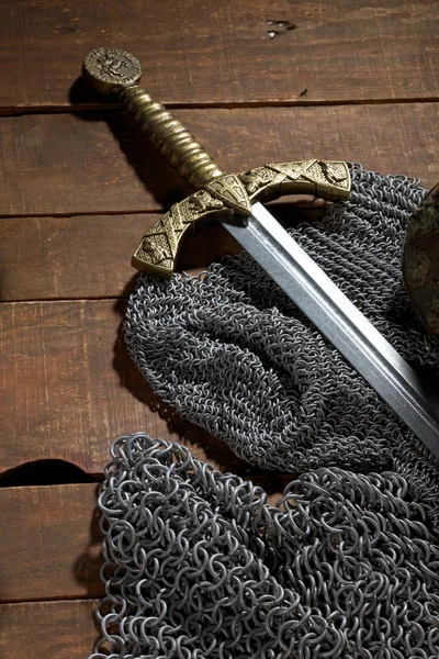 Schwert und Soldatenhelm mit Hörnern auf hölzernem Hintergrund — Stockfoto