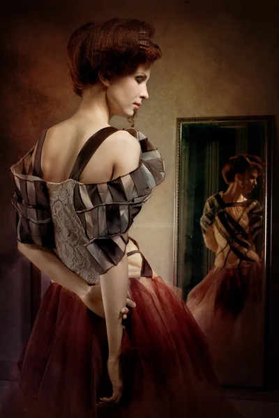Bir ayna yakınındaki fantastik elbiseli güzel kız