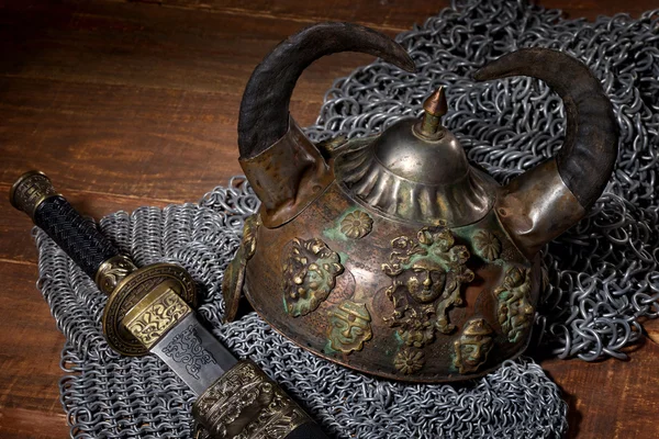 Sword and the soldier's helmet with horns on a wooden background — Stock Photo, Image