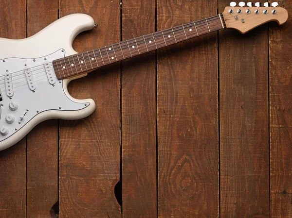 Fehér elektromos gitár egy fából készült háttér — Stock Fotó