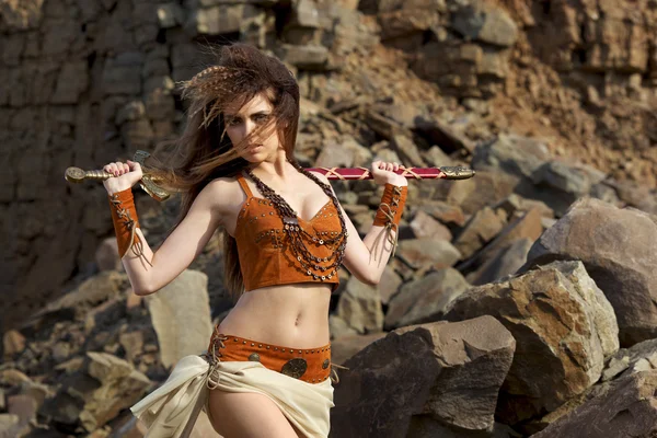 The beautiful girl with a sword in a suit of the amazon. — Stock Photo, Image