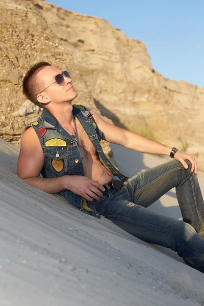 Porträt eines Mannes in Jeanskleidung im Sand. — Stockfoto