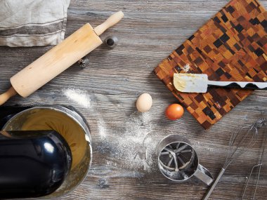 Ev mutfağında mikser, kek pişirmek için gerekli aletler ve diğer tatlılar olan bir masanın üst görüntüsü.