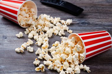 Taze patlamış mısır ve uzaktan kumandalı iki kağıt bardak tahta bir masanın üzerinde yatıyor..