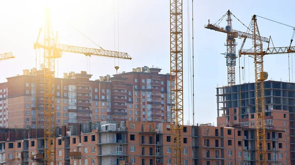 General view of the construction of a new residential complex. Multi-storey buildings and high-rise cranes.