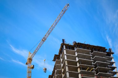 İnşaat süreci. Yüksek bir vinç, dökmek için bir kase betonu kaldırır..