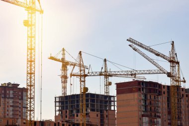 Bir konut kompleksinin inşaat süreci. Yeni binaların arka planına karşı birçok yüksek katlı vinç.