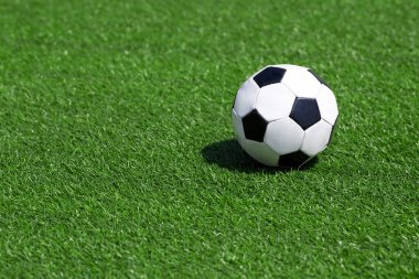Yeni yeşil bir sahada bir futbol topunun yakın çekimi. Hiç oyuncu yok..