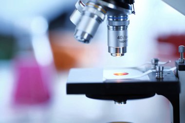 Modern bir optik mikroskoba yakın çekim, teçhizatlı bir laboratuarın arka planına karşı..