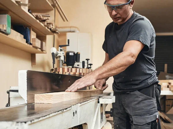 一位木匠在他的作坊里的木板磨床上工作 — 图库照片