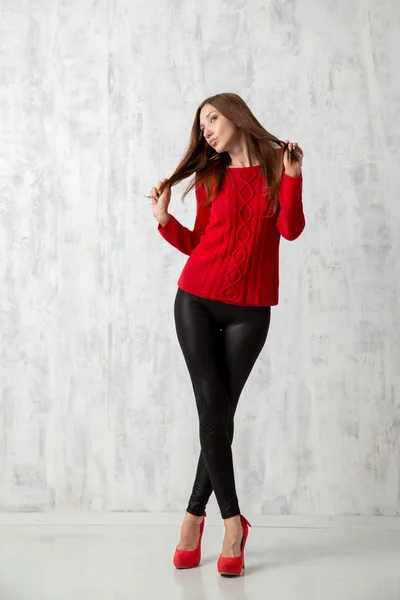 beautiful woman in red sweater in high heels posing