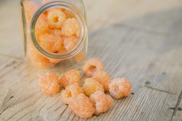 Cam kavanozda eski ahşap arka plan üzerinde renkli cam ahududu