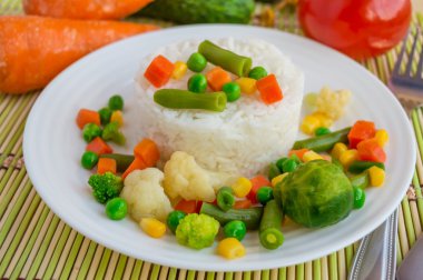 Pirinç Buhar ortaya konulan bir daire içinde beyaz bir plaka üzerinde pişmiş sebze ile. Vegan