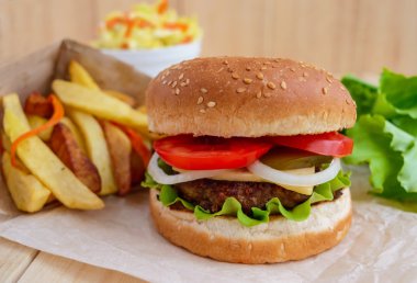 Sandviç ev hamburger yumuşak ekmeği, peynir, domates ve sulu hamburger. Lahana salatası. Patates kızartması. Fast food.