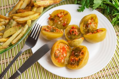 Baharatlı yeşil domates dolması maydanoz, acı biber, sarımsak beyaz bir plaka üzerinde