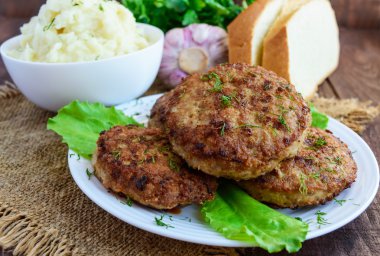 Sulu homecutlets (sığır eti, domuz eti, tavuk) ve ahşap bir arka plan üzerinde patates püresi