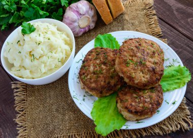 Sulu homecutlets (sığır eti, domuz eti, tavuk) ve ahşap bir arka plan üzerinde patates püresi