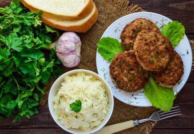 Sulu homecutlets (sığır eti, domuz eti, tavuk) ve ahşap bir arka plan üzerinde patates püresi