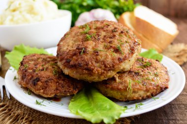 Sulu homecutlets (sığır eti, domuz eti, tavuk) ve ahşap bir arka plan üzerinde patates püresi