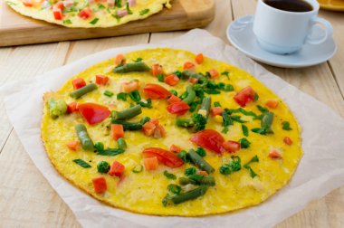 Tahta bir arka plan üzerinde sebzeli omlet ve bir fincan coffe. Kahvaltı