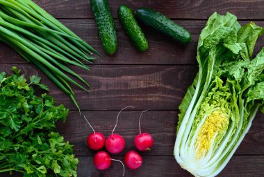 Taze yeşil sebze (lahana, salatalık), yeşil soğan, maydanoz ve turp ahşap arka plan üzerinde. Salata için. Üstten Görünüm