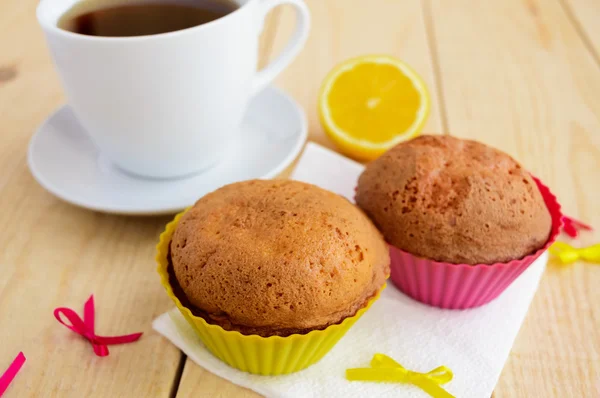 Lekkie cytryny cupcakes babeczki na podłoże drewniane i filiżankę herbaty — Zdjęcie stockowe