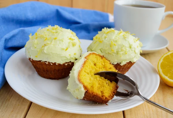 Cupcake al limone leggeri muffin su sfondo di legno e una tazza di tè . — Foto Stock