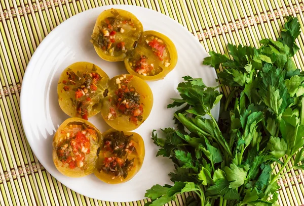 Baharatlı yeşil domates dolması maydanoz, acı biber, sarımsak beyaz bir plaka üzerinde