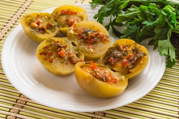 Baharatlı yeşil domates dolması maydanoz, acı biber, sarımsak beyaz bir plaka üzerinde