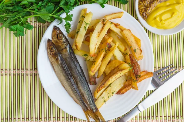 Gebakken aardappelen (frietjes) "at home" met een kleine gerookte vis — Stockfoto