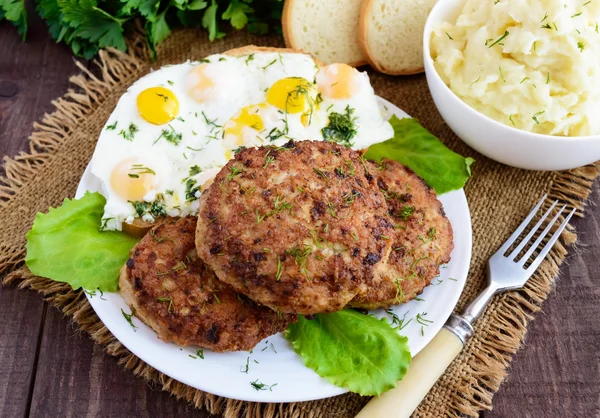 Chuletas caseras jugosas (carne de res, cerdo, pollo) huevos fritos y puré de papas sobre un fondo de madera —  Fotos de Stock