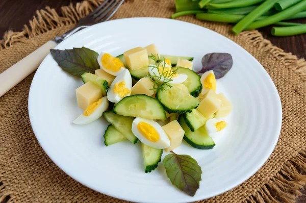 Lehká italská jarní salát s čerstvou okurku, křepelčí vejce, mozzarella, olivový olej na bílé plotně na dřevěné pozadí. Dietní jídlo — Stock fotografie