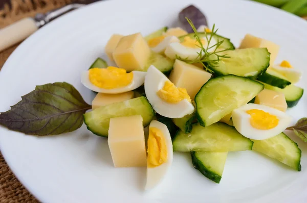 木製の背景の白いプレートにイタリアの春サラダ新鮮なキュウリ、ウズラの卵、モッツァレラチーズ、オリーブ オイルを光します。 — ストック写真
