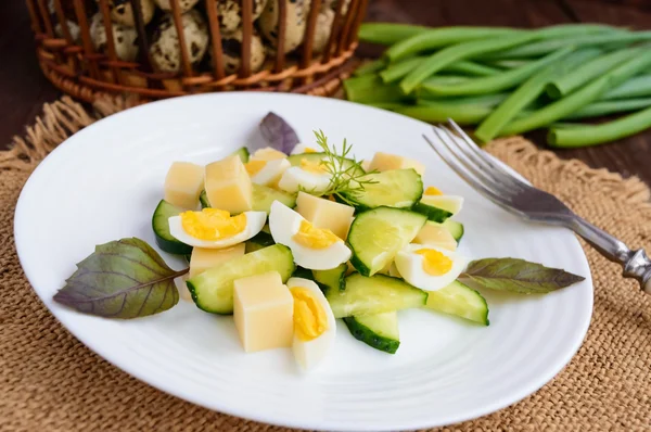 Salade de printemps italienne légère avec concombre frais, œufs de caille, mozzarella, huile d'olive sur une assiette blanche sur un fond en bois — Photo