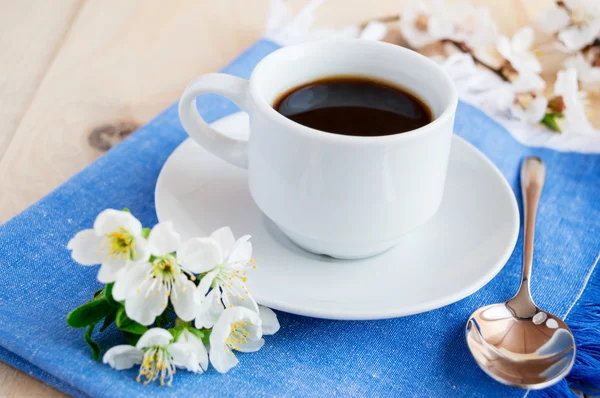 Cup of coffee on a blue napkin. Spring flowers