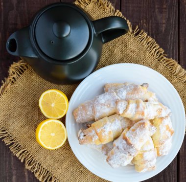 Tatlı ev yapımı limonlu kruvasanları pudra şekeri ile. Çaydanlık