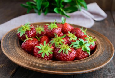 Olgun çilek bir kil kase ve nane yaprağı. ahşap arka plan yakın çekim.